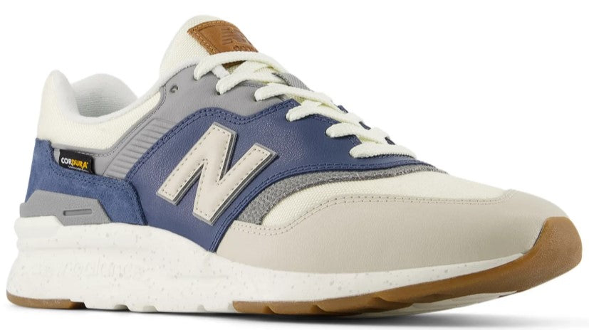 A low-rise trainer with off-white canvas, white midsole, and blue suede trim around the heel and quarter panels, displaying a large gray and white letter N.