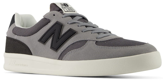 A low-top sneaker in shades of grey with a dark grey N logo on the side, mesh and suede upper, and a thick off-white rubber sole, with 300 printed on the tongue tag.