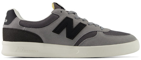 A gray suede and mesh low-top sneaker featuring a large black 'N' logo on the side, a dark gray heel tab, and a white rubber cupsole.