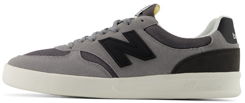 A low-top grey suede and mesh sneaker with a black N logo on the side, a black heel panel, and a cream-colored midsole.