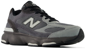 A New Balance 990v6 running shoe in a grey and black colorway featuring a mesh and suede upper, a prominent white N logo on the side, and a chunky, dark-toned midsole.