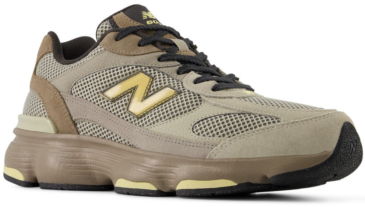 A New Balance 9060 sneaker in earth tones featuring mesh and suede overlays, a prominent yellow N logo on the side, dark laces, and a chunky, sculpted midsole in brown and yellow.
