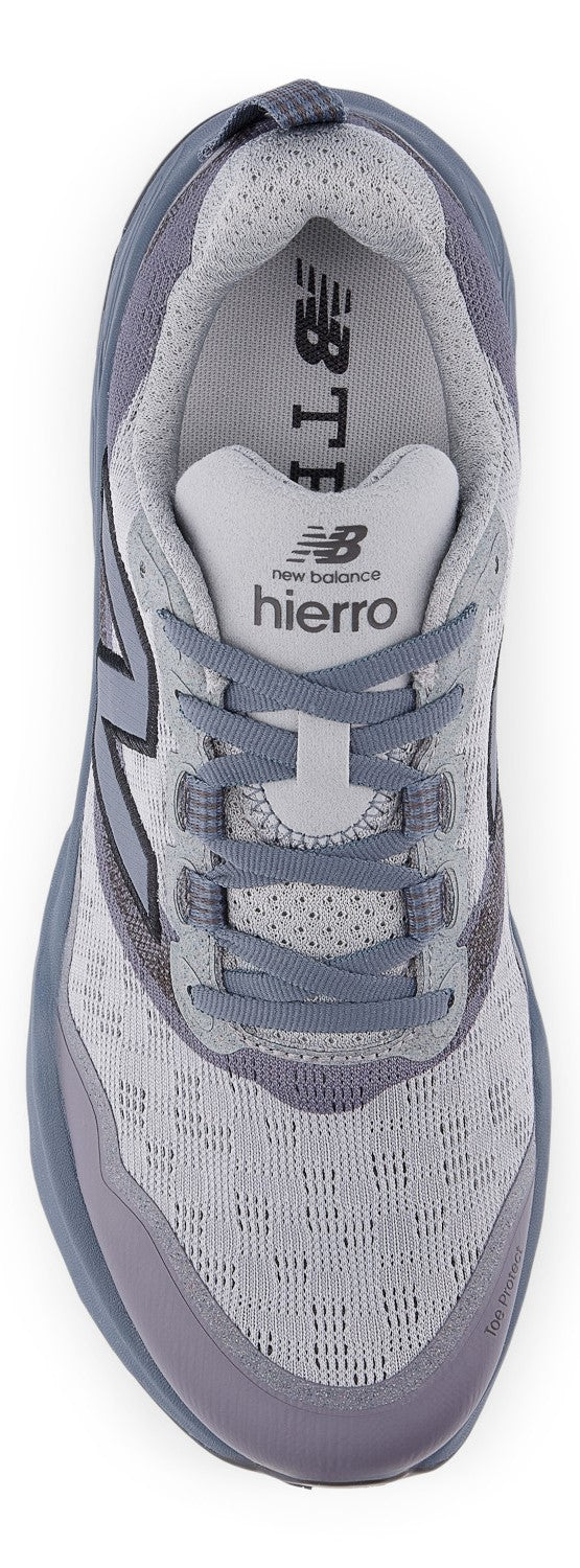 A top-down view of a light gray and purple athletic running shoe with laces, featuring the visible text NEW BALANCE and HIERRO on the tongue.