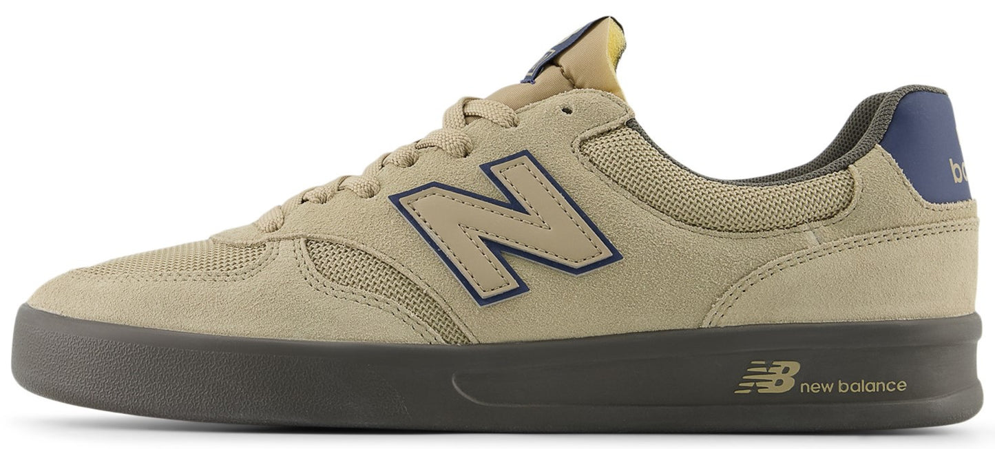 A tan sneaker with a navy blue N logo and grey sole.