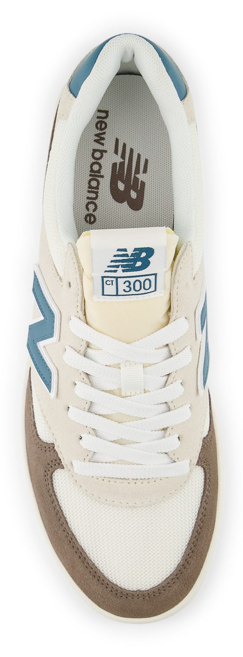 Overhead view of a sneaker with off-white laces and a brown toe. Inside the shoe, the words "new balance" are printed.