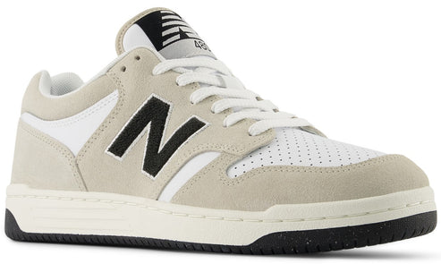 Low-top sneaker with a white toe and heel, beige suede accents, black "N" logo, and a black and white logo on the tongue.