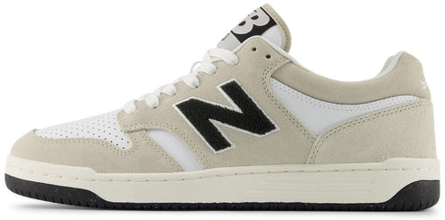 A New Balance low top sneaker in off-white with black accents.