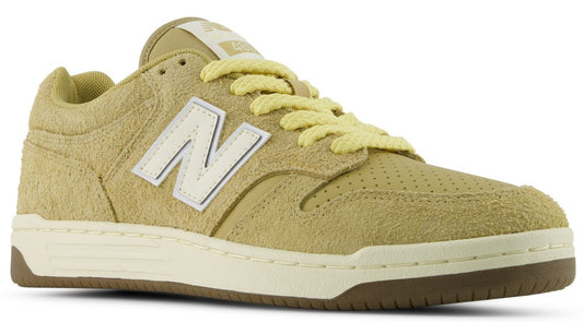A low-top athletic shoe with a hairy, light olive-green suede upper, featuring a white capital N logo on the side, cream-colored laces, a perforated toe box, a white midsole, and a brown rubber outsole.