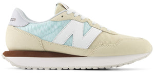 A sneaker with a beige suede upper, white laces, a white "N" logo, and a thick white sole.