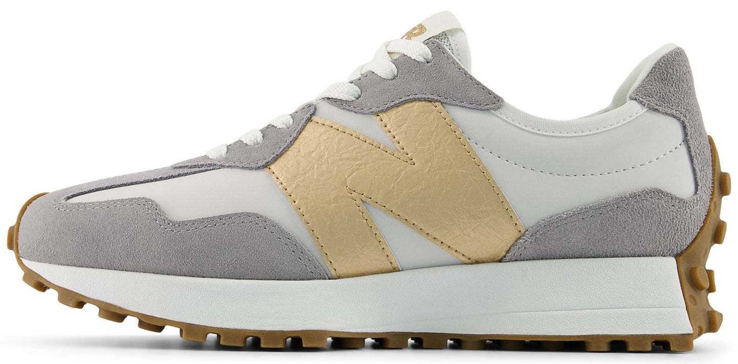 A New Balance 327 sneaker featuring a grey suede and white nylon upper with a gold leather "N" logo on the side.