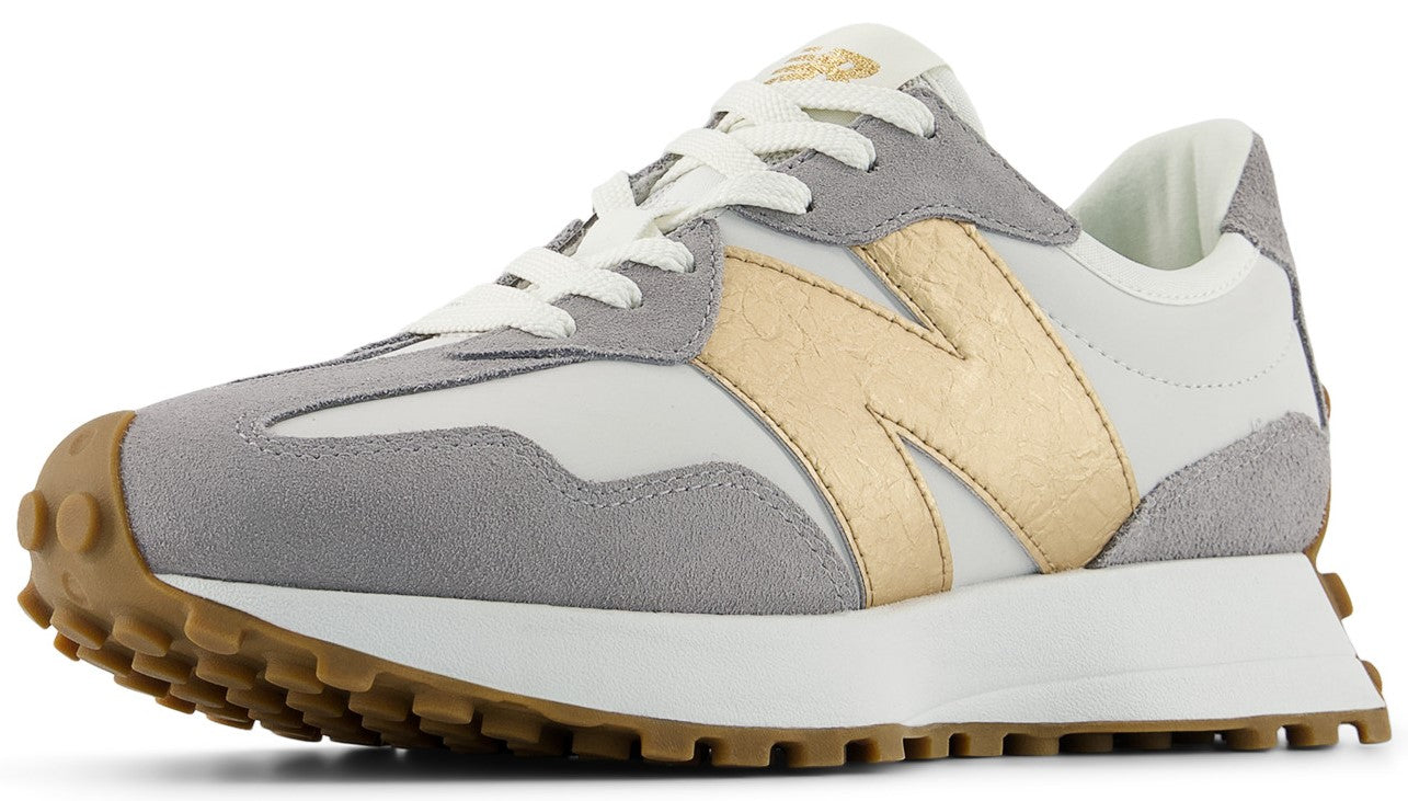 A low-rise sneaker with a white textile upper, grey suede accents, gold logo, white laces, and a brown lug sole.
