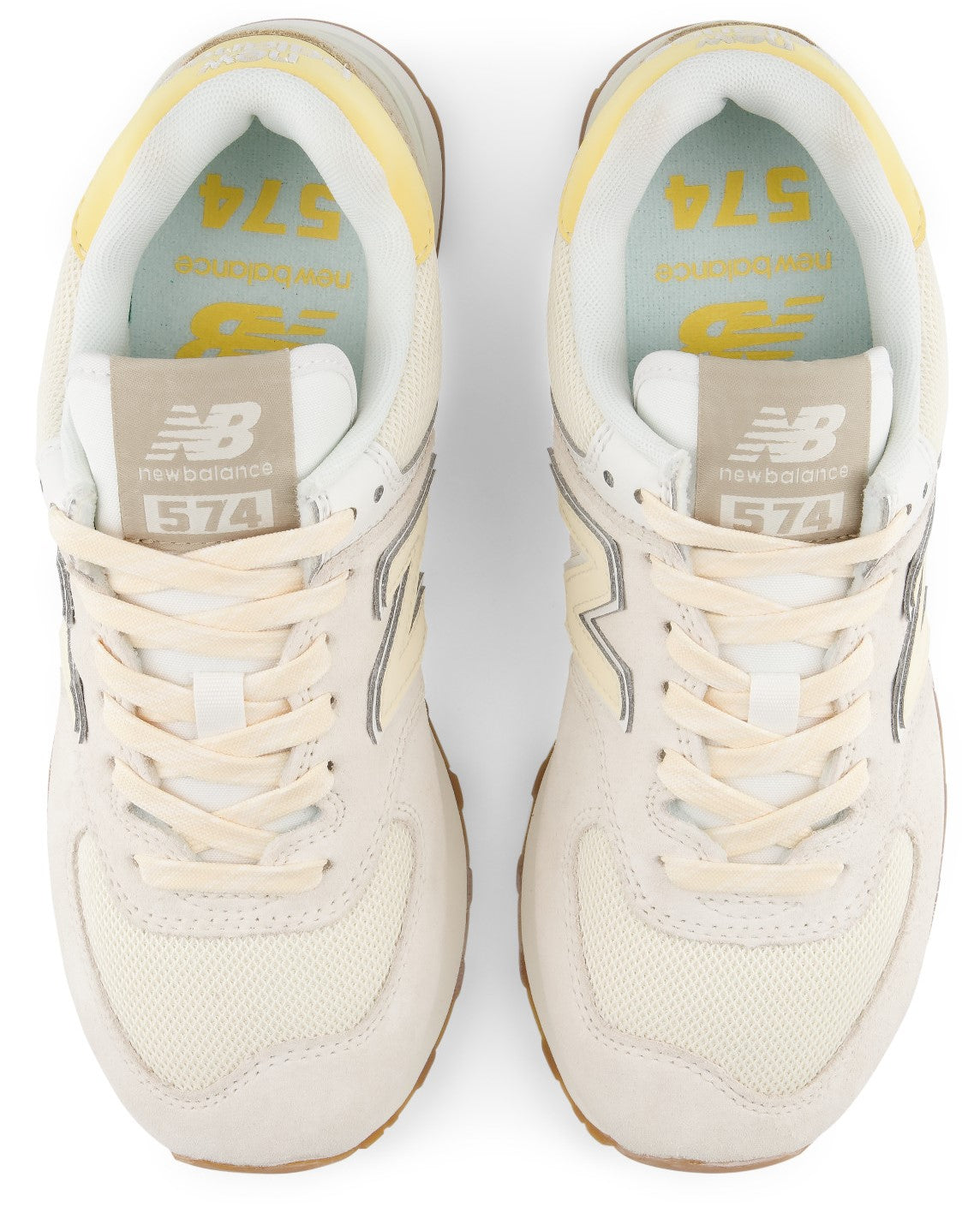 A pair of top-down view of cream-colored New Balance 574 athletic shoes featuring a mesh and suede upper, light yellow collar trim, and branded insoles with the number 574.