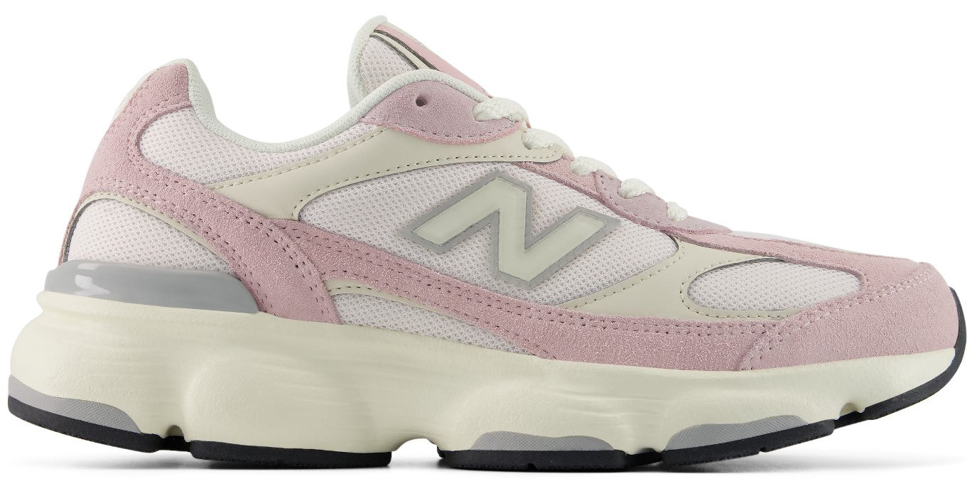 A lifestyle sneaker with a pastel pink suede and white mesh upper, featuring a prominent N logo on the side, a chunky off-white midsole, and a black rubber outsole.