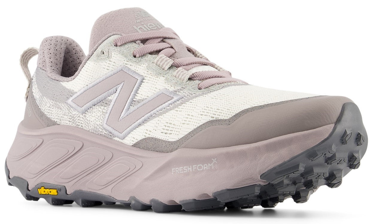 A light mauve and white trail running shoe with a textured fabric upper, a thick Fresh Foam X midsole, and a grey lugged Vibram outsole.