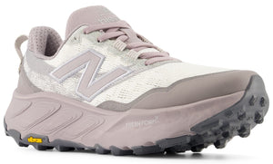 A light mauve and white trail running shoe with a textured fabric upper, a thick Fresh Foam X midsole, and a grey lugged Vibram outsole.