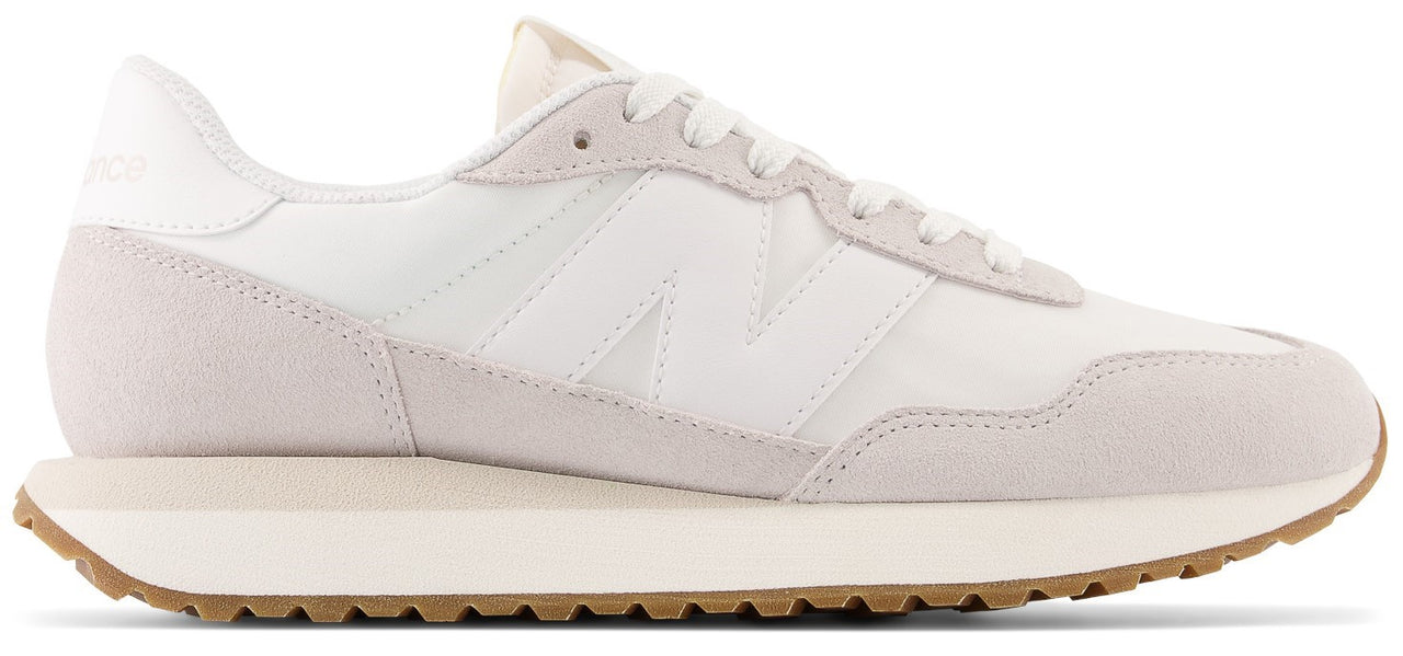 A white sneaker with a beige sole and the letter N on the side.