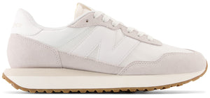 A white sneaker with a beige sole and the letter N on the side.