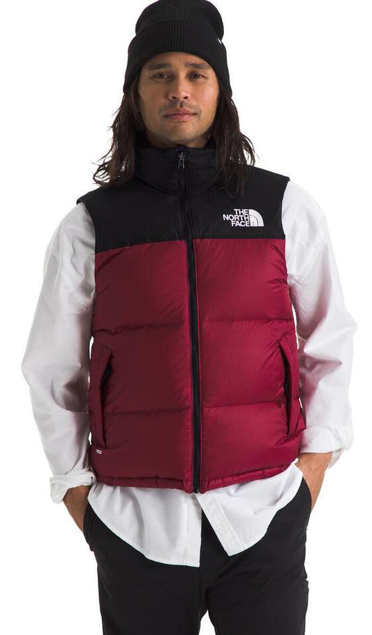 A man wearing a black beanie, black and red puffer vest, and white collared shirt.