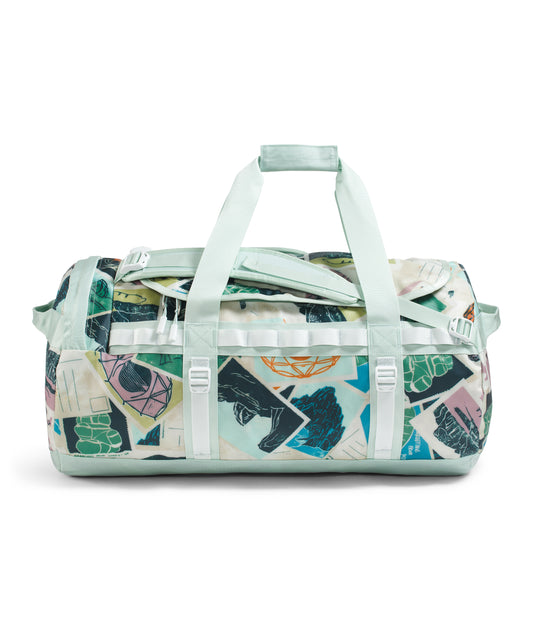 Duffel bag with light blue handles and straps, in a collage of various geometric and organic shapes with dark blue, green, yellow, pink, black and white colors.