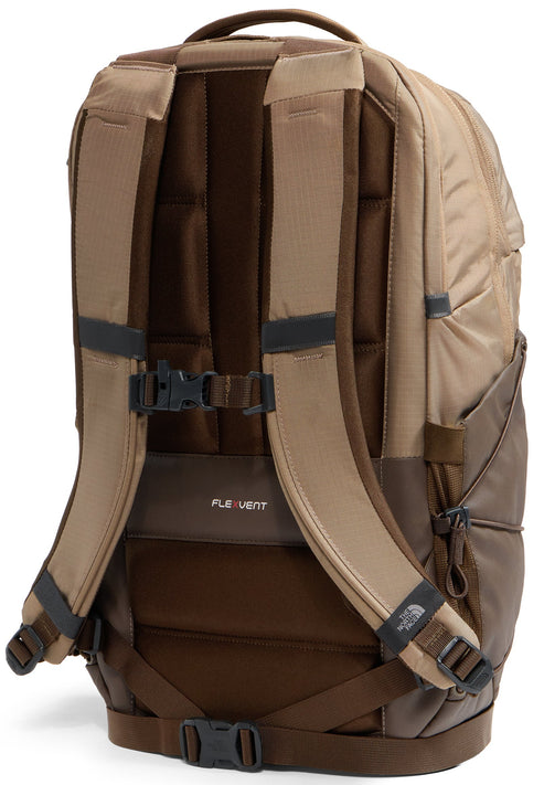 A tan and dark brown backpack shown from the back, featuring padded shoulder straps with a chest buckle, a FlexVent logo on the back panel, and a bottom waist buckle strap.