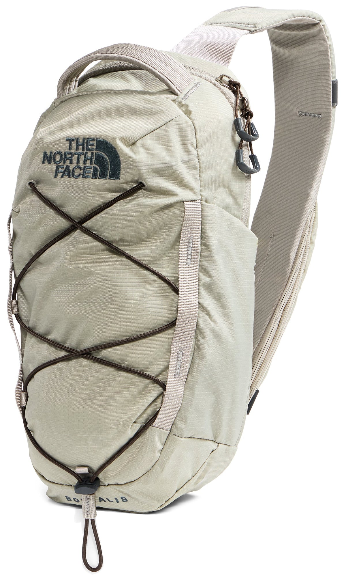 A light beige, single-strap sling backpack with a dark green bungee cord lacing system on the front, a grab handle at the top, and the text The North Face printed at the top center, with the word Borealis printed near the bottom.