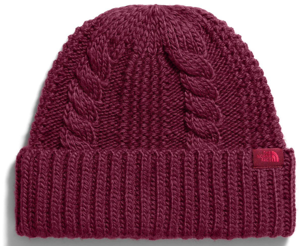 A maroon-colored cuffed beanie with a cable-knit pattern on the crown and a ribbed pattern on the brim, featuring a small tag with The North Face logo on the lower right side.