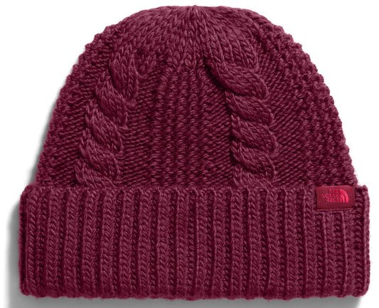 A maroon-colored cuffed beanie with a cable-knit pattern on the crown and a ribbed pattern on the brim, featuring a small tag with The North Face logo on the lower right side.