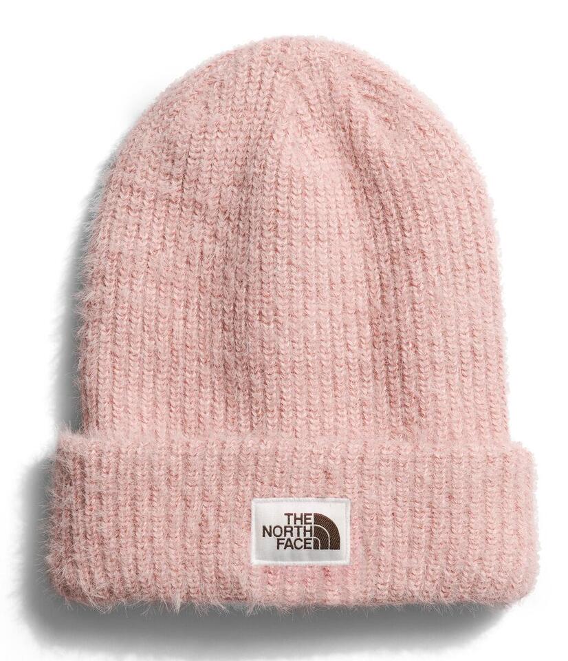 Close-up of a pink knit beanie with a visible logo patch on the folded brim that reads "The North Face".