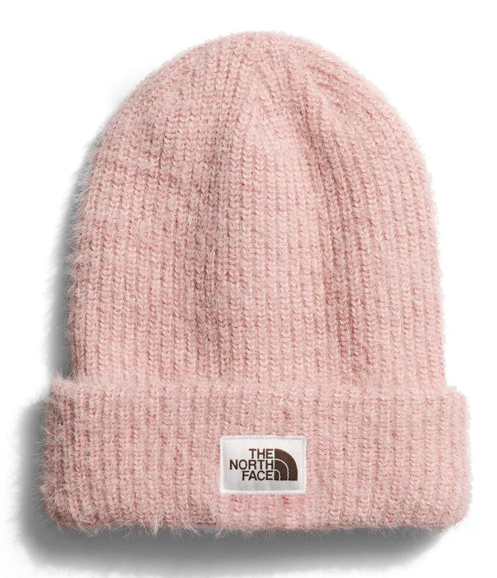 Close-up of a pink knit beanie with a visible logo patch on the folded brim that reads "The North Face".