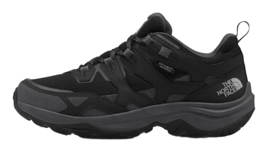 A black low top trail shoe with a thick treaded sole and white logo on the heel.