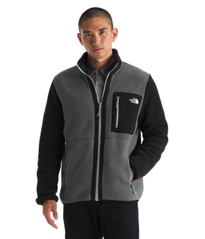 Man wearing a two-tone fleece jacket in gray and black with a zipper closure and a pocket on the chest.