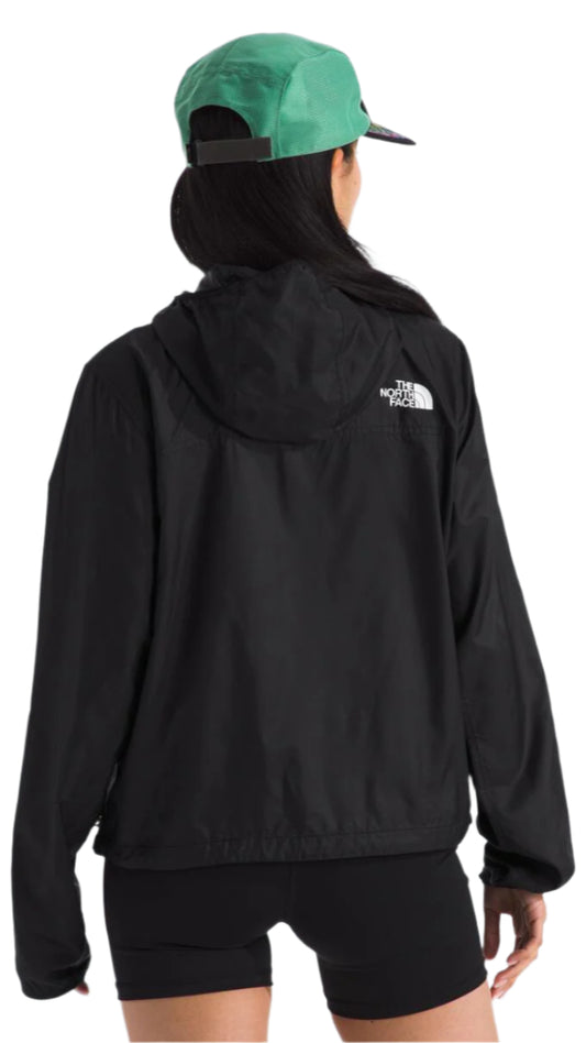 A person is shown from the back wearing a black jacket with a hood and a green cap.