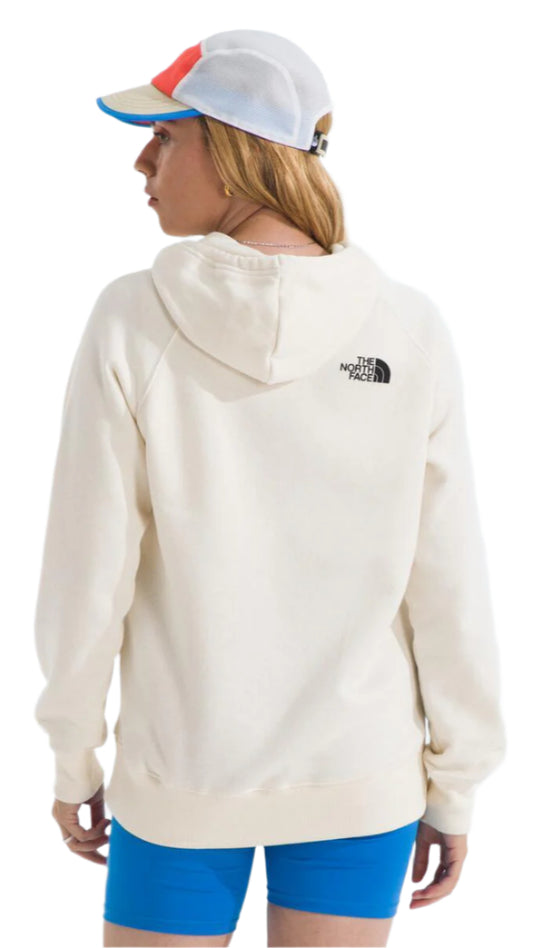 A person wearing a white hoodie, blue shorts, and a multi-colored cap, shown from the back.