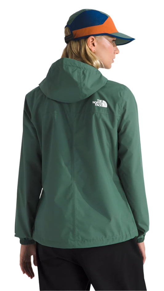 A woman wearing a green jacket with a hood, back view, and a colorful baseball cap.