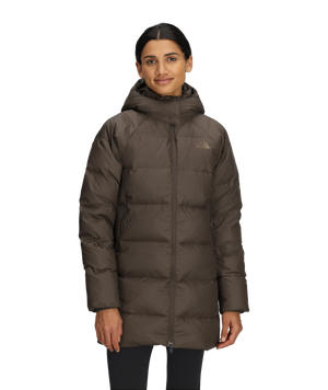 A person wearing a brown, knee-length puffer coat with a hood.