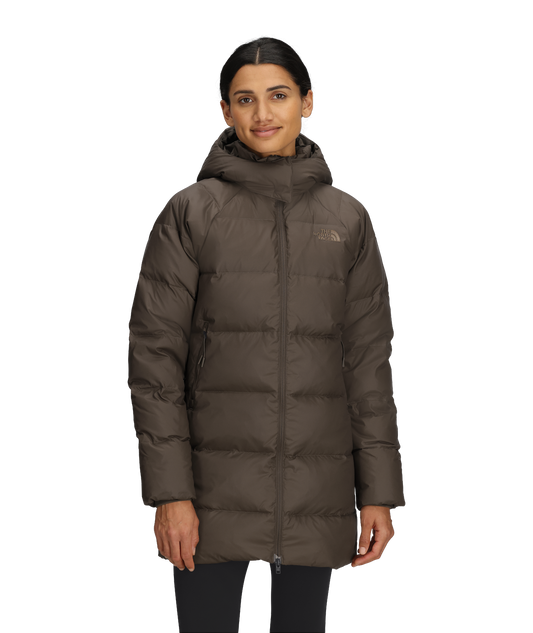 A person wearing a brown, knee-length puffer coat with a hood.