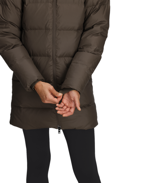 Midsection view of a person in a brown puffer coat and black leggings.