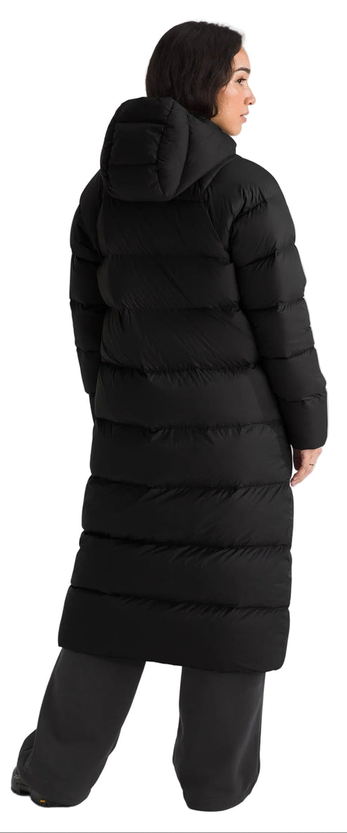 A person is wearing a black puffer coat with a hood and wide-legged pants.