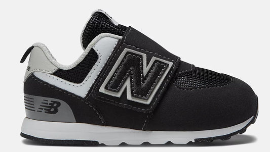 A black New Balance toddler shoe with white and gray accents, featuring a large 'N' logo and a velcro strap.