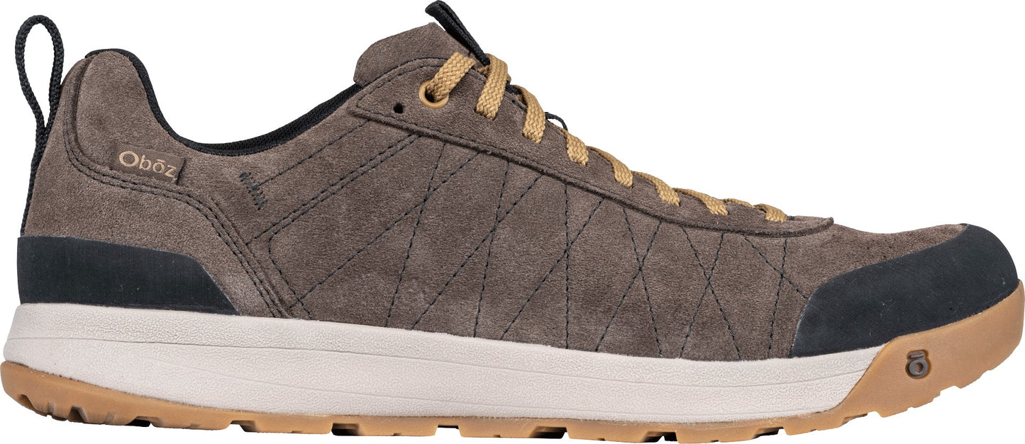 A brown suede hiking shoe with tan laces, a white midsole, a gum-colored treaded outsole, and a black reinforced toe and heel, featuring the word Oboz on the side.