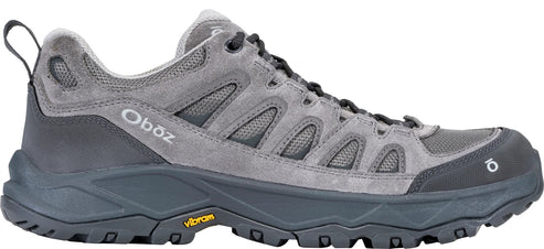A gray low-top Oboz hiking shoe with a suede and mesh upper, a dark gray midsole, a thick lugged Vibram outsole, and an Oboz logo on the side.