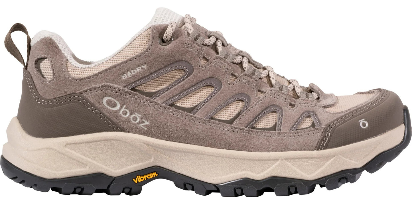 A light brown and beige hiking shoe with a rugged black Vibram rubber sole, mesh panels, and Oboz branding visible on the side and near the toe.
