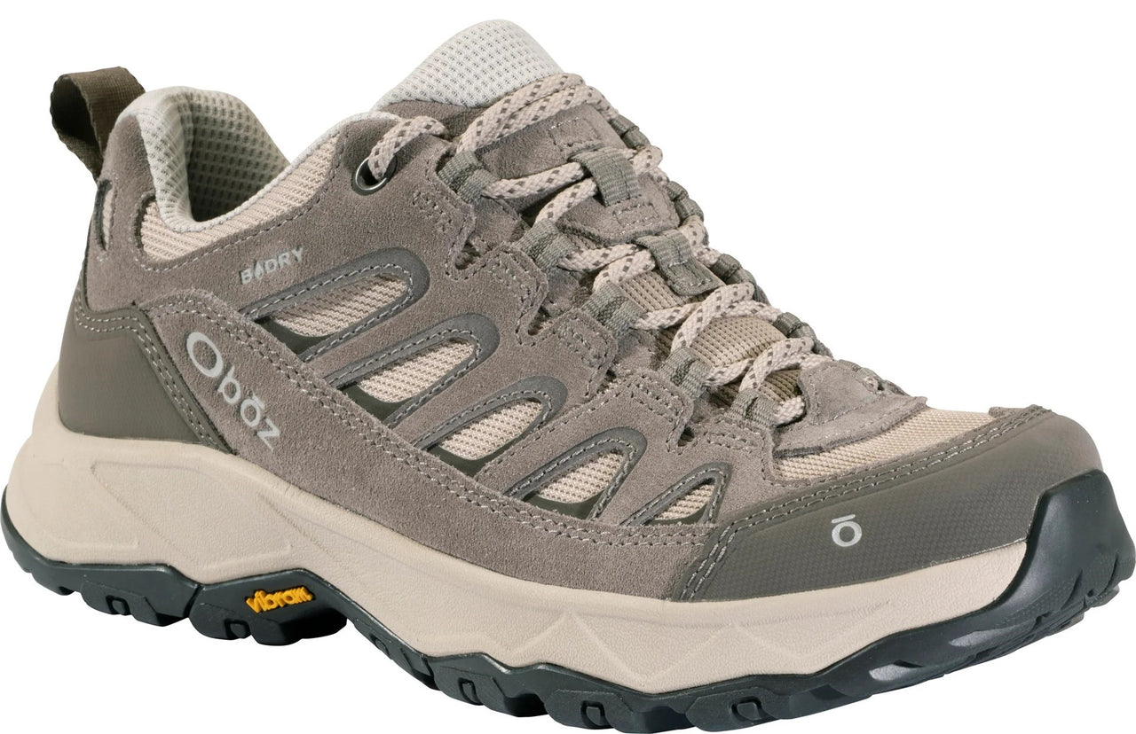 A low-top taupe-colored hiking shoe with suede and mesh upper, patterned laces, a thick beige midsole, a dark grey Vibram rubber outsole, and the Oboz logo on the side heel and front toe.