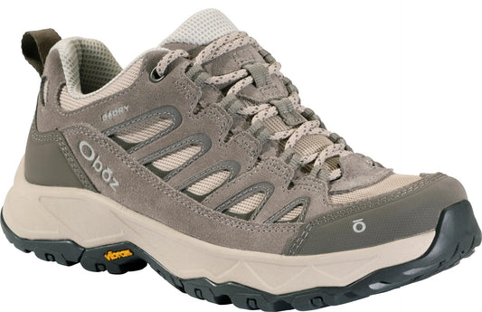 A low-top taupe-colored hiking shoe with suede and mesh upper, patterned laces, a thick beige midsole, a dark grey Vibram rubber outsole, and the Oboz logo on the side heel and front toe.