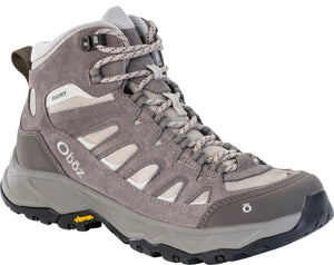 A gray mid-cut hiking boot with mesh panels and suede overlays, featuring a B-DRY label on the ankle, an Oboz logo on the heel, a Vibram logo on the side of the sole, and a black toe bumper.
