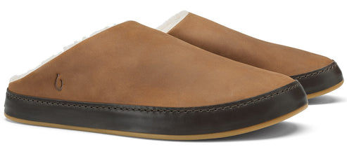 A pair of tan leather slip-on slippers with a dark brown leather mudguard and a light-colored shearling lining, featuring a small logo stamped on the side.