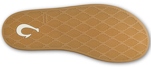 The tan-colored rubber outsole of a sandal featuring an embossed repeating pattern of stylized leaves, with a white, hook-shaped logo symbol near the heel.