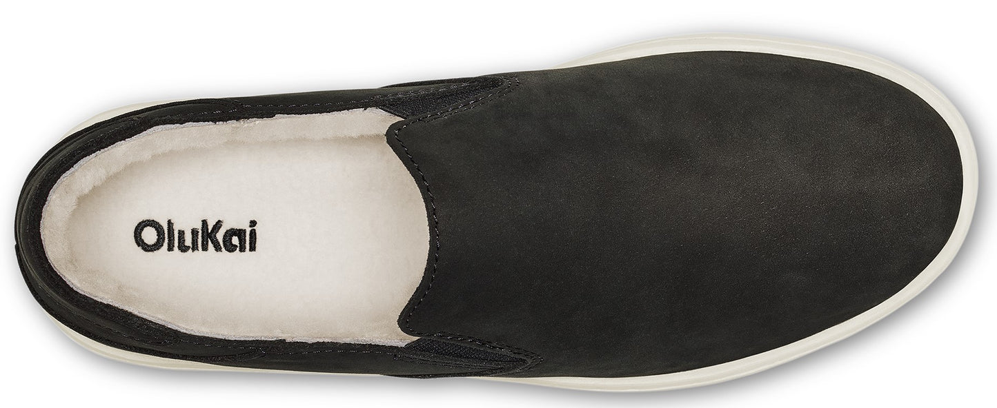 Overhead shot of black slip-on shoe with white interior and white sole, featuring 'OluKai' logo inside.