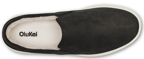 Overhead shot of black slip-on shoe with white interior and white sole, featuring 'OluKai' logo inside.