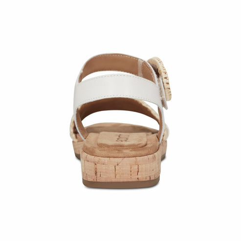 White sandal with adjustable ankle strap, cork sole, and round rattan-style buckle.